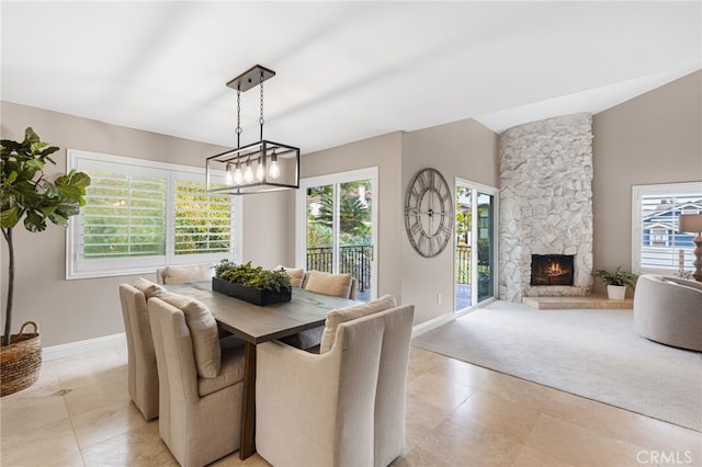 dining space with lofted ceiling, a wealth of natural light, light colored carpet, and a fireplace