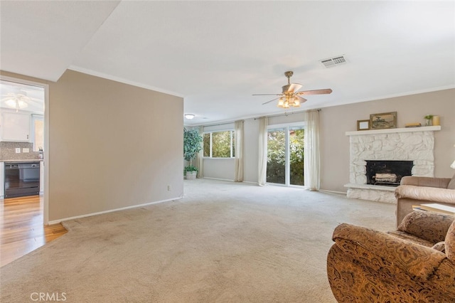 carpeted living room with ceiling fan, crown molding, and a fireplace