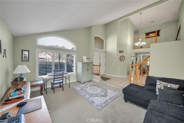 carpeted living room with a notable chandelier and high vaulted ceiling