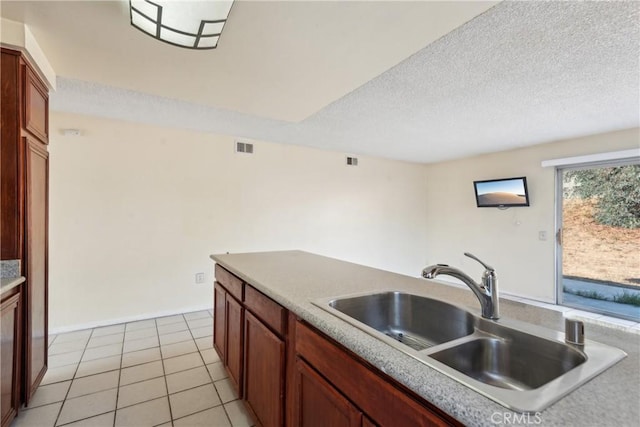 kitchen with sink, light tile patterned floors, and a textured ceiling