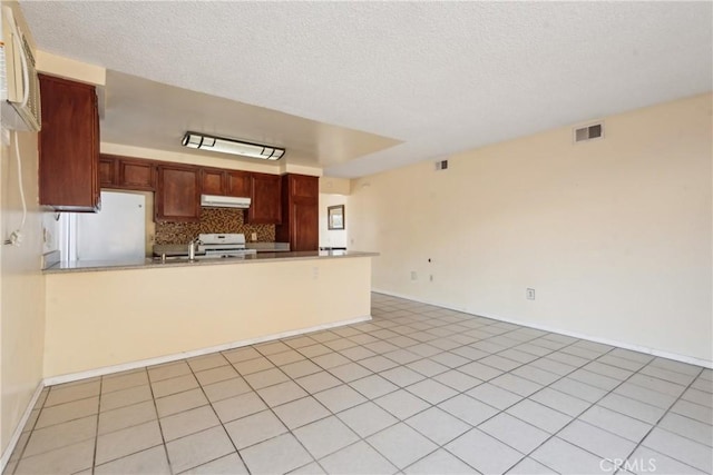 kitchen with tasteful backsplash, white appliances, kitchen peninsula, and a textured ceiling