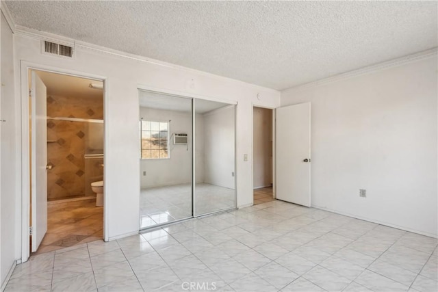 unfurnished bedroom with crown molding, ensuite bathroom, a textured ceiling, and a closet