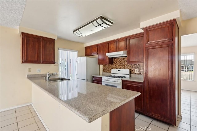 kitchen featuring white appliances, kitchen peninsula, sink, and light stone countertops