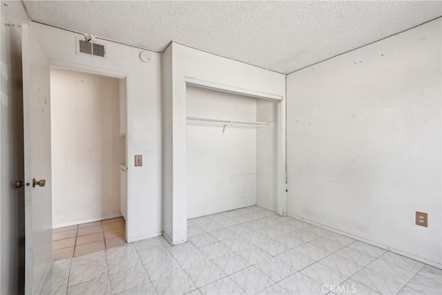 unfurnished bedroom with a textured ceiling and a closet