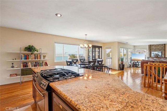 kitchen with pendant lighting, plenty of natural light, stainless steel range with gas stovetop, and light wood-type flooring