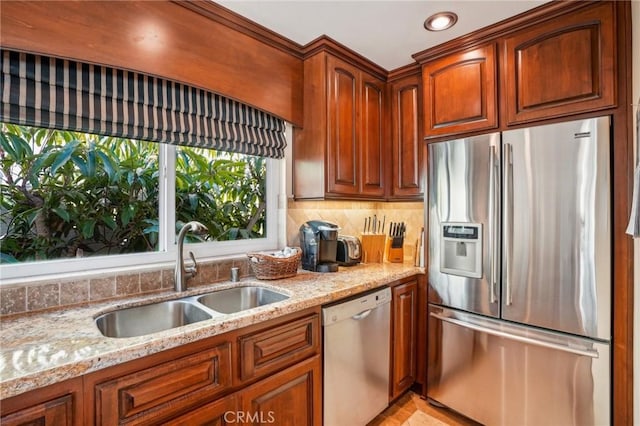 kitchen with tasteful backsplash, appliances with stainless steel finishes, sink, and light stone counters