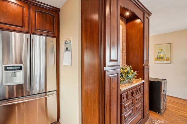 kitchen featuring light stone counters, light hardwood / wood-style floors, and stainless steel fridge with ice dispenser