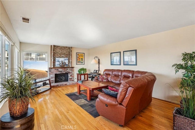 living room with hardwood / wood-style flooring and a brick fireplace