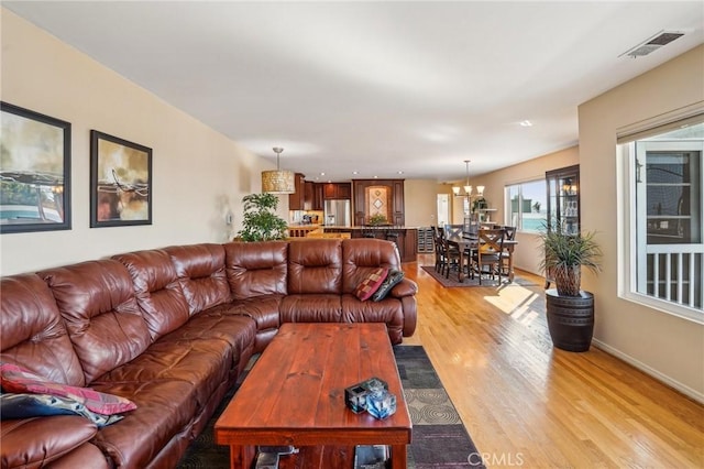 living room with an inviting chandelier and light wood-type flooring