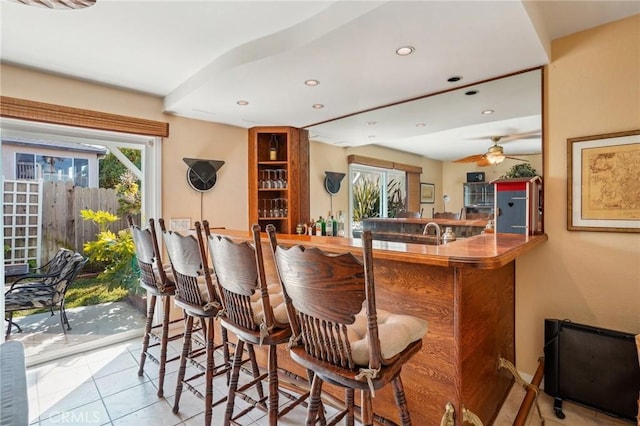 bar featuring light tile patterned floors, sink, and ceiling fan