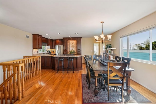 dining room featuring a water view, a notable chandelier, and light hardwood / wood-style flooring