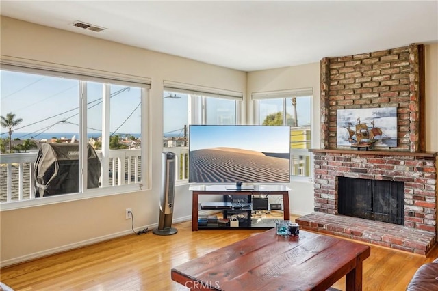 living room featuring a brick fireplace and wood-type flooring