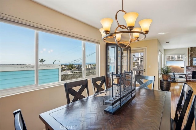 dining space with a fireplace, a chandelier, and dark parquet floors