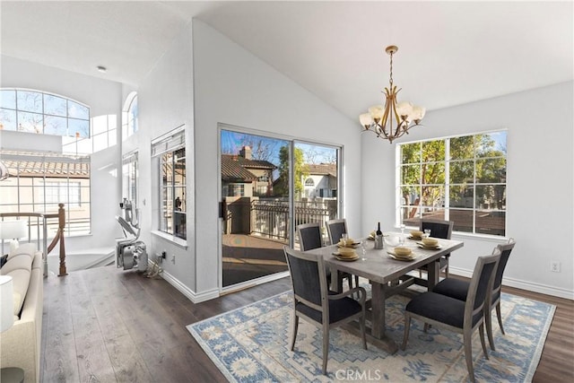 dining room with high vaulted ceiling, dark hardwood / wood-style floors, and an inviting chandelier