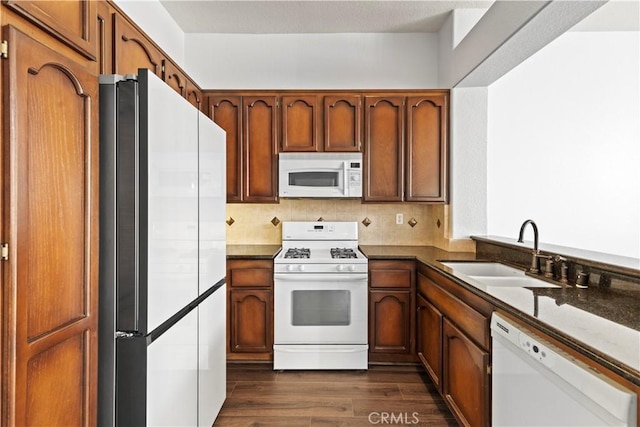 kitchen featuring white appliances, dark hardwood / wood-style floors, sink, and backsplash