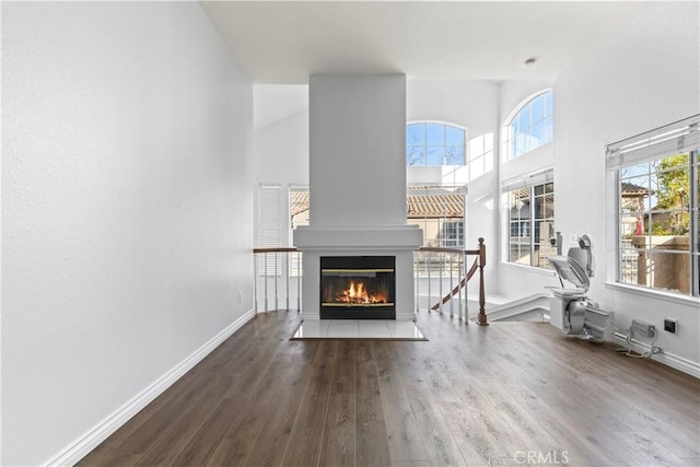 unfurnished living room featuring hardwood / wood-style flooring, a healthy amount of sunlight, and a towering ceiling