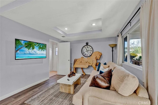 living room with hardwood / wood-style floors and a tray ceiling