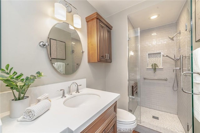 bathroom featuring vanity, toilet, and a shower with shower door