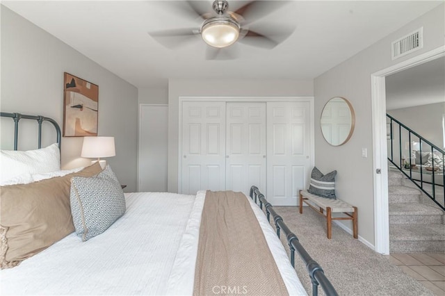 bedroom with light colored carpet, ceiling fan, and a closet