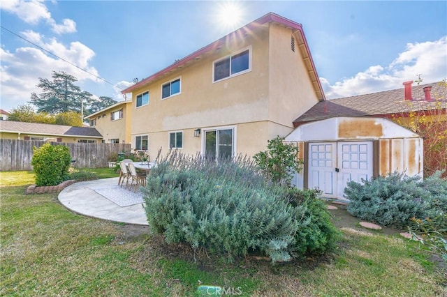 back of house featuring a patio, an outdoor structure, and a lawn