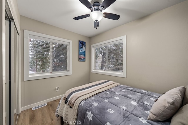 bedroom featuring dark wood-type flooring, ceiling fan, and multiple windows