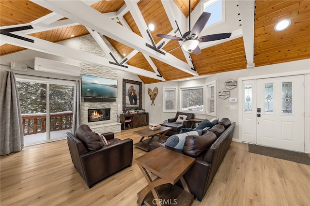 living room featuring wood ceiling, a stone fireplace, ceiling fan, and light wood-type flooring