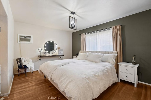 bedroom featuring dark hardwood / wood-style flooring and a wall mounted AC