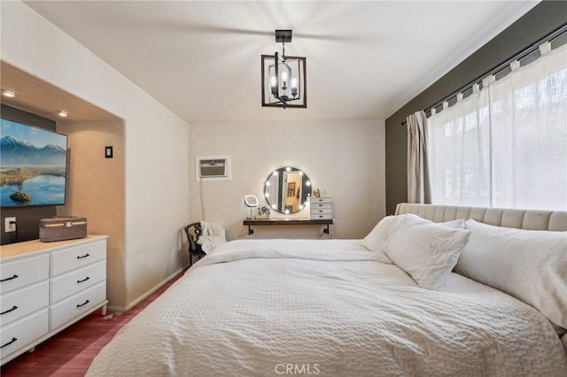 bedroom featuring a notable chandelier, dark wood-type flooring, and a wall mounted AC