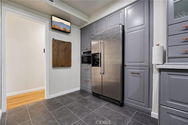 kitchen with appliances with stainless steel finishes, gray cabinets, and dark tile patterned flooring