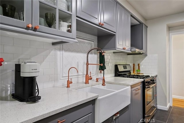 kitchen featuring sink, gray cabinetry, dark tile patterned floors, light stone countertops, and stainless steel range with gas stovetop