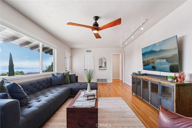 living room featuring a water view, ceiling fan, rail lighting, and light hardwood / wood-style floors