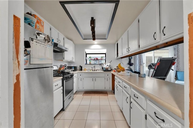kitchen with white cabinets, stainless steel appliances, light countertops, light tile patterned floors, and a sink