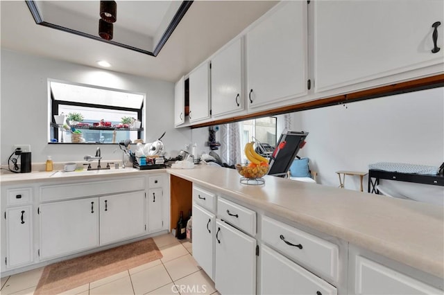 kitchen featuring white cabinetry, sink, and light tile patterned flooring