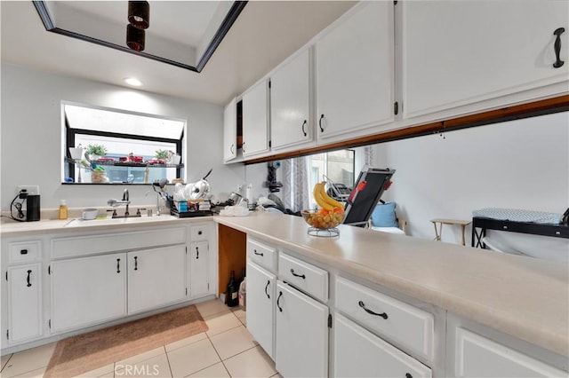 kitchen featuring white cabinets, light tile patterned flooring, a sink, and light countertops