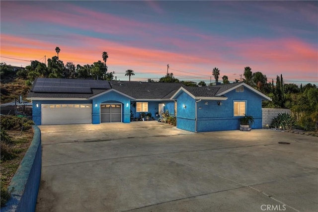 ranch-style house with a garage and solar panels