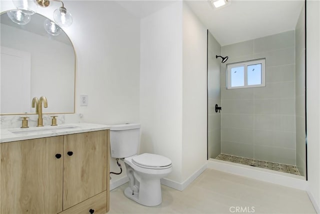 bathroom with tiled shower, vanity, and toilet