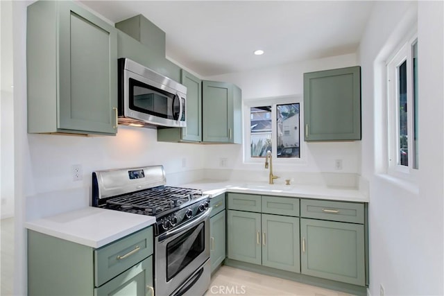 kitchen with sink, green cabinets, and appliances with stainless steel finishes