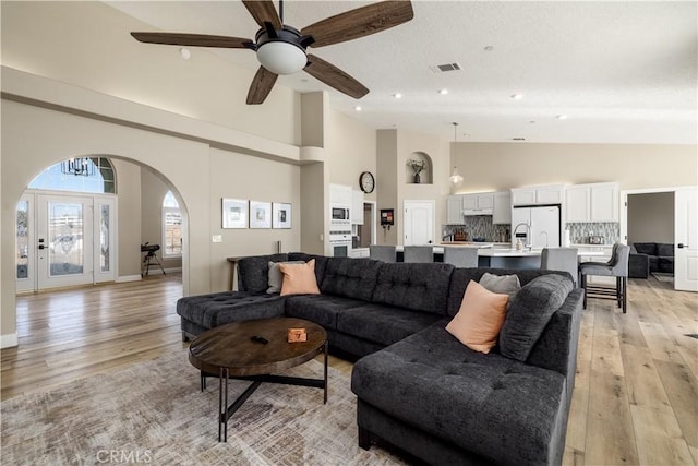 living room with high vaulted ceiling, light hardwood / wood-style floors, and ceiling fan