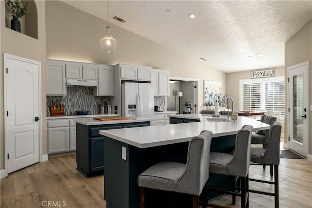 kitchen featuring white cabinetry, sink, white refrigerator with ice dispenser, and an island with sink