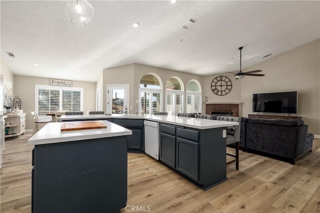 kitchen featuring lofted ceiling, a fireplace, a center island, and light wood-type flooring