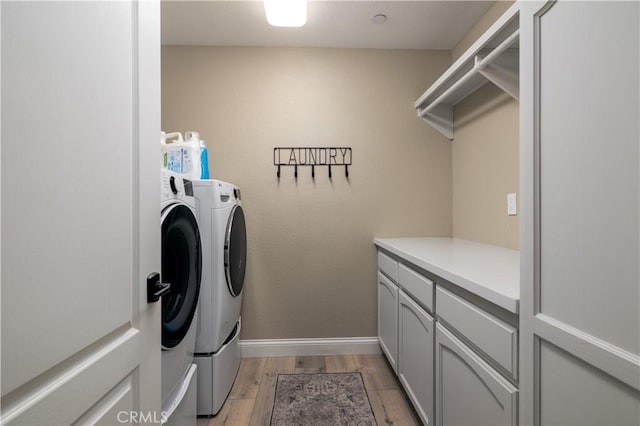 washroom featuring cabinets, separate washer and dryer, and light hardwood / wood-style flooring