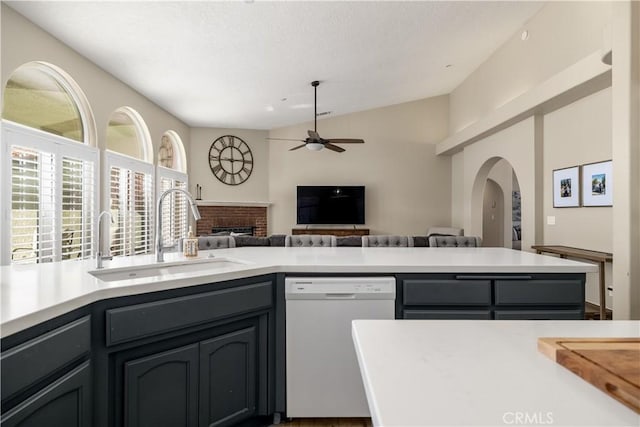 kitchen with sink, ceiling fan, dishwasher, gray cabinetry, and a brick fireplace