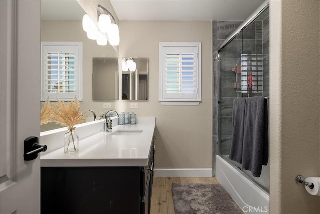 bathroom featuring hardwood / wood-style flooring, vanity, and shower / bath combination with glass door