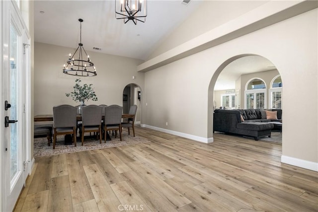 dining area with light wood-type flooring and a notable chandelier