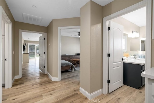 corridor featuring sink and light hardwood / wood-style flooring