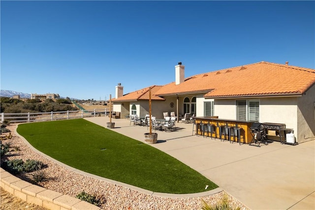 rear view of house featuring a bar, a yard, and a patio area