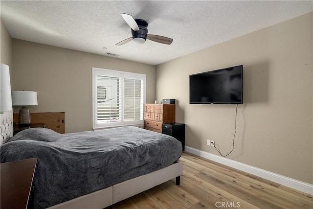 bedroom featuring ceiling fan, light hardwood / wood-style flooring, and a textured ceiling