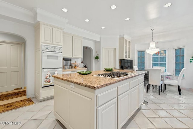 kitchen featuring pendant lighting, double oven, a center island, stainless steel gas cooktop, and white cabinets