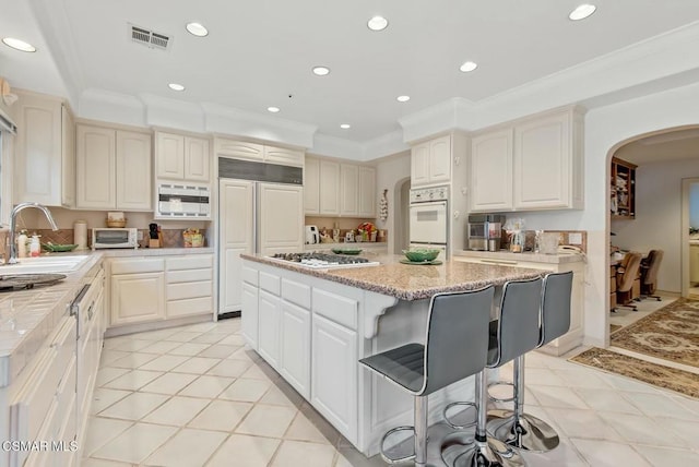 kitchen featuring built in appliances, sink, ornamental molding, and a center island