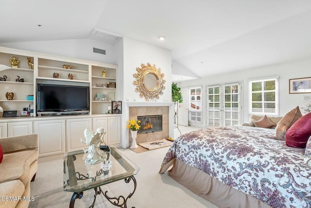 bedroom featuring lofted ceiling, a tiled fireplace, and light colored carpet